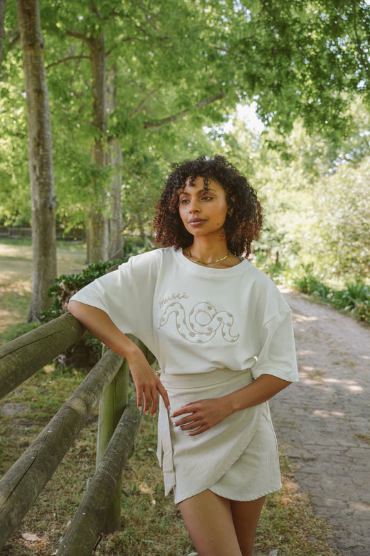 Woman standing outdoors in a natural setting, wearing Serpent embroidered t-shirt
