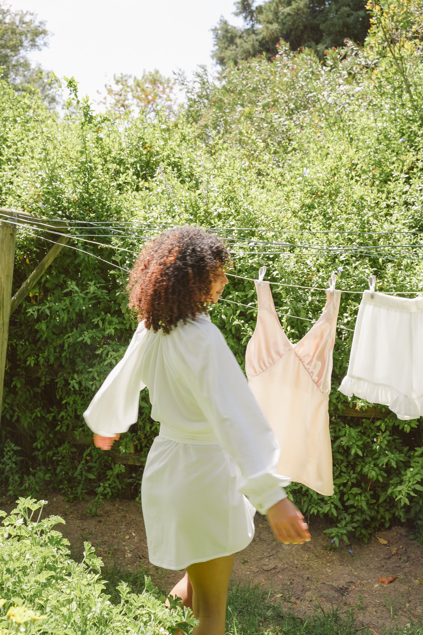 Model hanging clothes on a clothesline in a garden