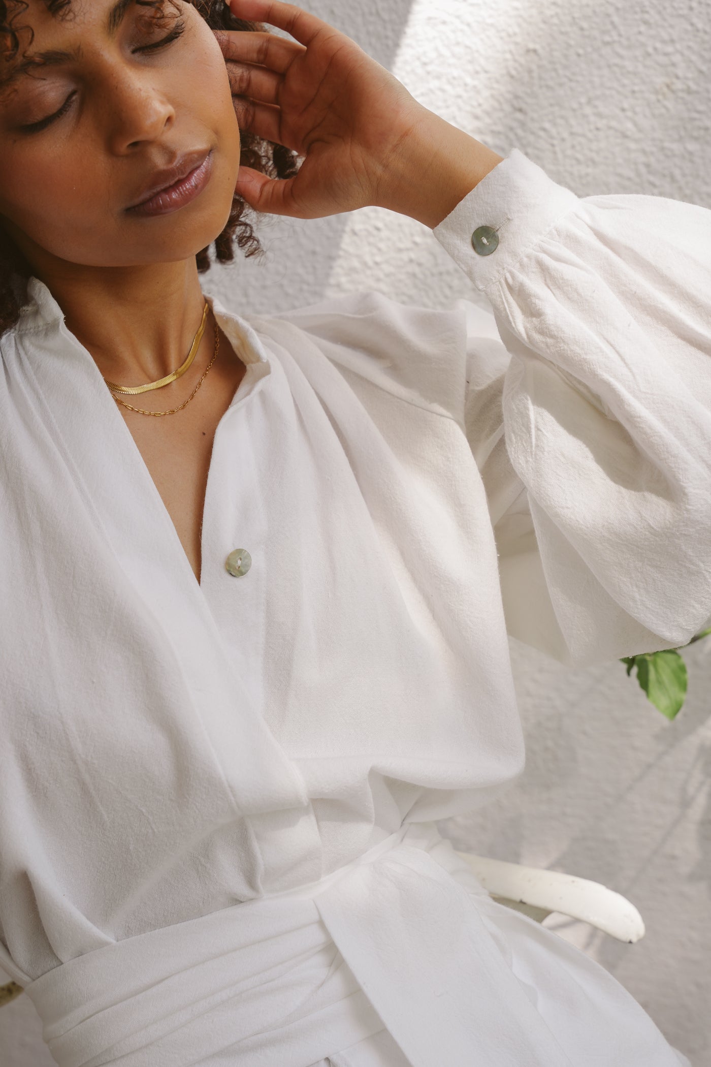 Woman wearing a white achak dress with a textured wall background