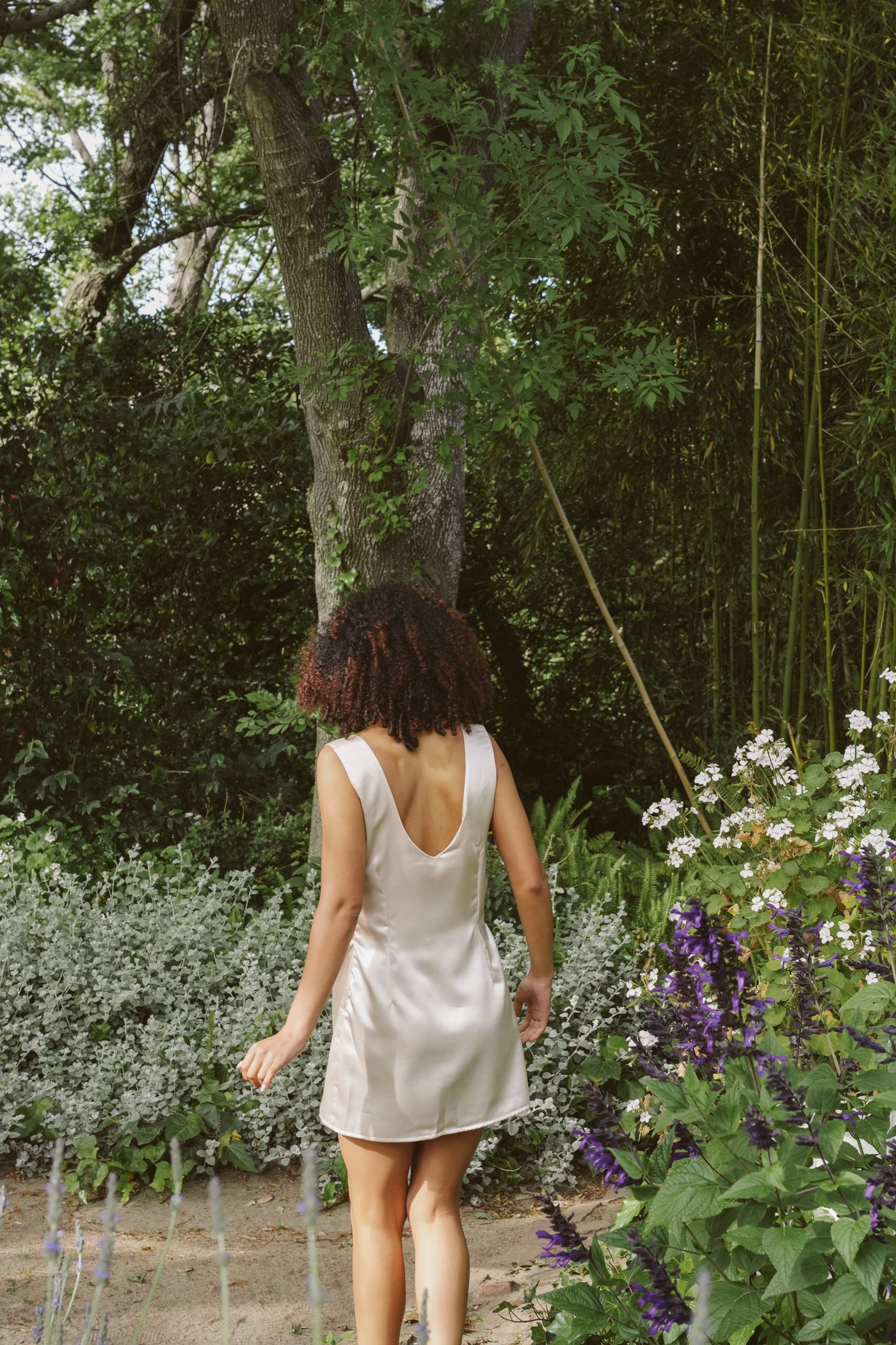 Woman walking through the forest wearing Museā Champagne Slip Dress.