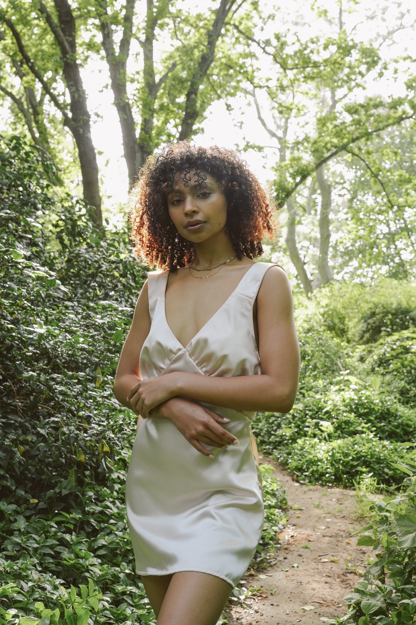 Woman standing calmly in the forest wearing Museā Champagne Slip Dress.