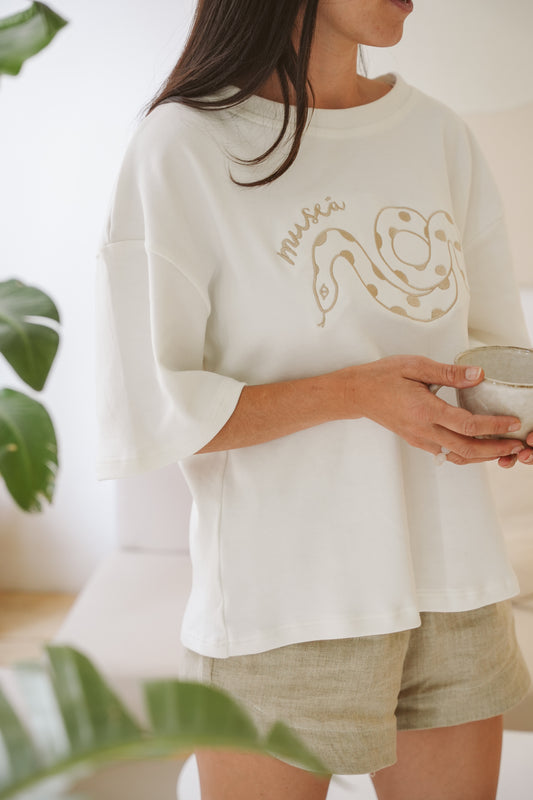 Model wearing cotton Museā Serpent T-Shirt while drinking tea.