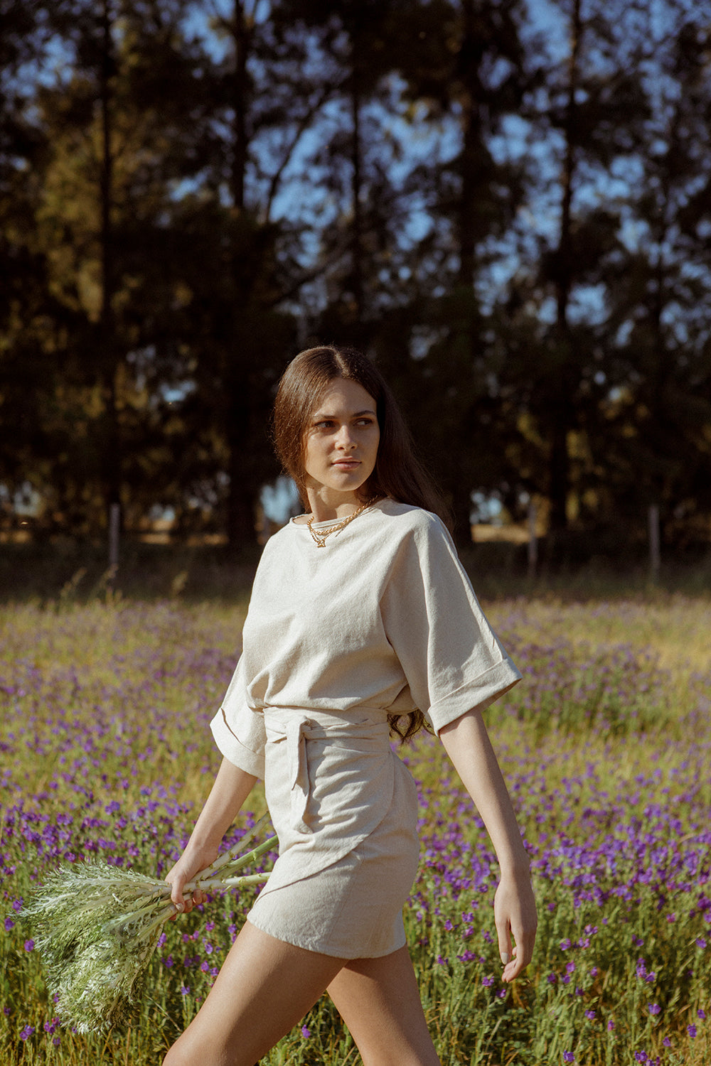 Model walking across a field wearing a cotton linen wrap skirt
